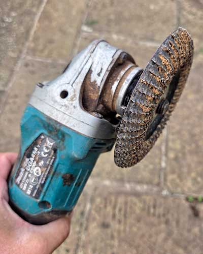 Cordless angle grinder fitted with a wood carving disc