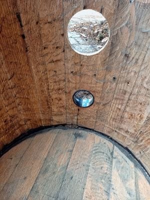 Inside a barrel owl box looking up at the entrance hole with the round camera pocket below it