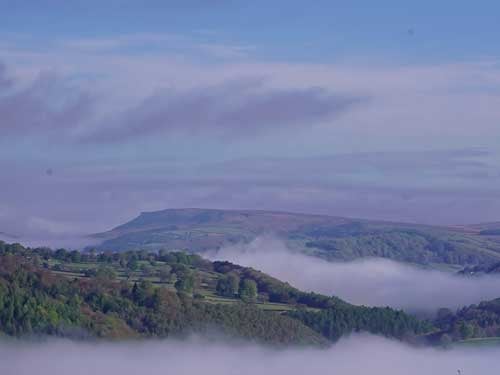 Morning mist lying in the Derwent Valley below autumn woodland in the Peak District